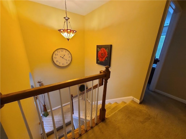 stairway featuring baseboards and carpet flooring