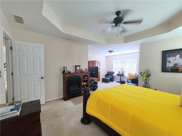 bedroom with baseboards, visible vents, light colored carpet, a tray ceiling, and a fireplace