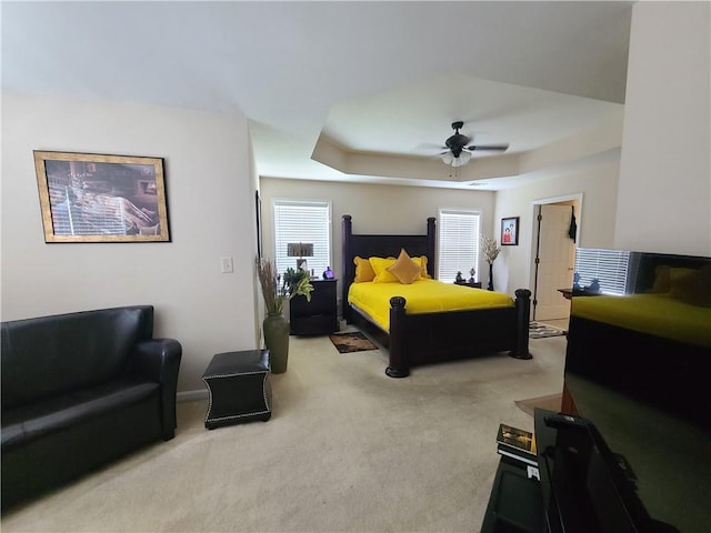 bedroom featuring a ceiling fan, a raised ceiling, and light carpet