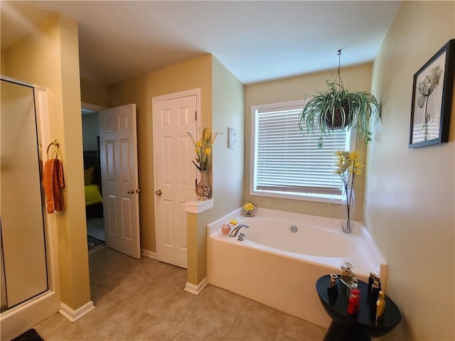 bathroom with a shower stall, baseboards, a bath, and tile patterned floors