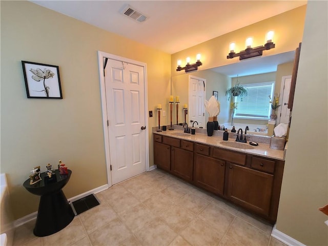 bathroom with double vanity, baseboards, visible vents, and a sink