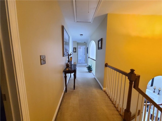 corridor with attic access, baseboards, light carpet, and an upstairs landing