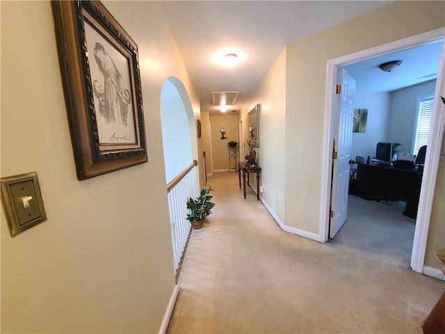 corridor featuring light carpet, attic access, and baseboards