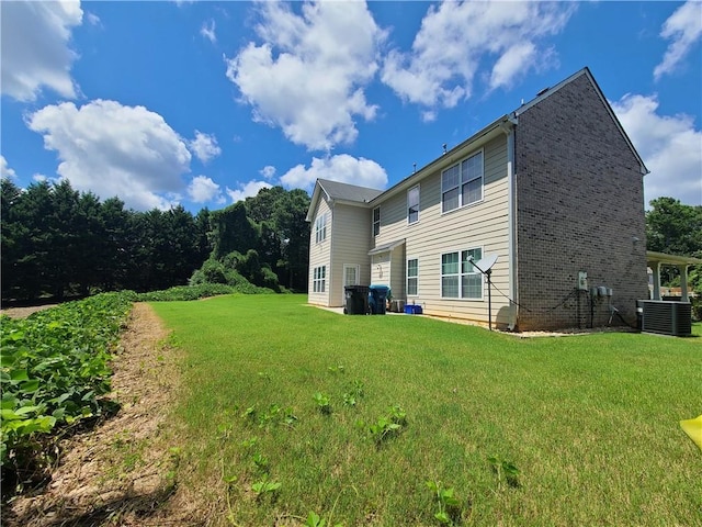 back of house featuring central AC, brick siding, and a lawn