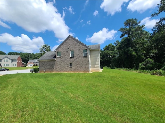 view of side of home featuring brick siding and a lawn