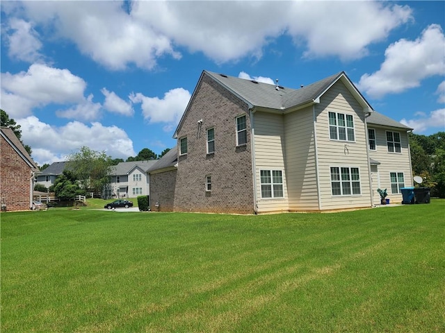 rear view of house with brick siding and a lawn