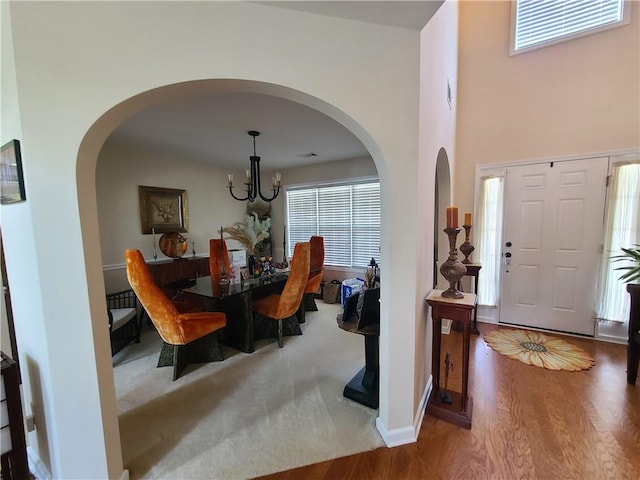 dining room with arched walkways, plenty of natural light, wood finished floors, and a notable chandelier