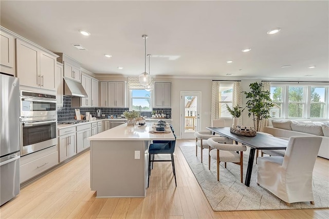 82 Sheryl Way, Loganville, GA 30052 - kitchen with appliances with stainless steel finishes, under cabinet range hood, decorative backsplash, light countertops, and a kitchen bar