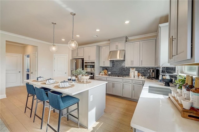 82 Sheryl Way, Loganville, GA 30052 - kitchen featuring under cabinet range hood, appliances with stainless steel finishes, a breakfast bar area, decorative backsplash, and light countertops