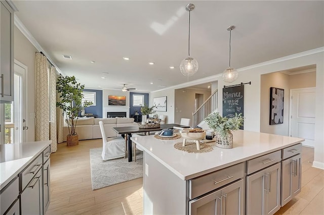 82 Sheryl Way, Loganville, GA 30052 - kitchen with gray cabinets, light countertops, ornamental molding, light wood-type flooring, and pendant lighting