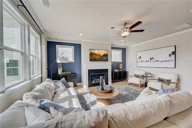 82 Sheryl Way, Loganville, GA 30052 - living area with healthy amount of natural light, ornamental molding, ceiling fan, wood finished floors, and a glass covered fireplace