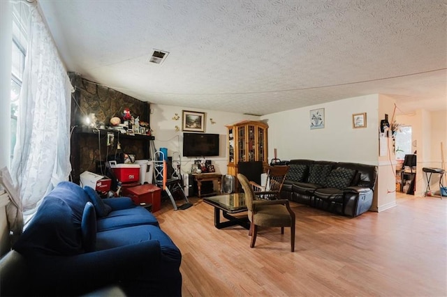 living room featuring a textured ceiling, visible vents, and wood finished floors