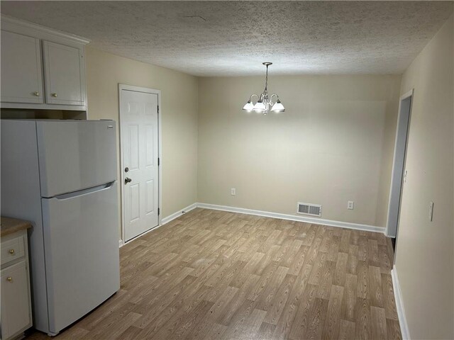 1106 Hardy Cir, Dallas, GA 30157 - unfurnished dining area featuring visible vents, light wood-type flooring, a chandelier, and a textured ceiling