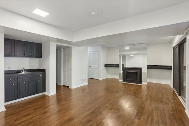 49 Willow Gln, Atlanta, GA 30342 - unfurnished living room featuring dark wood finished floors, a fireplace, bar with sink, and baseboards