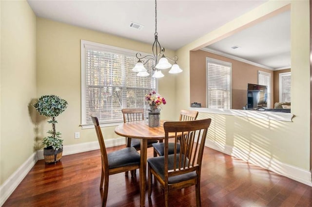 dining area with crown molding, dark hardwood / wood-style flooring, and an inviting chandelier