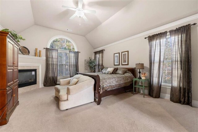 bedroom with ceiling fan, lofted ceiling, light carpet, and a tiled fireplace