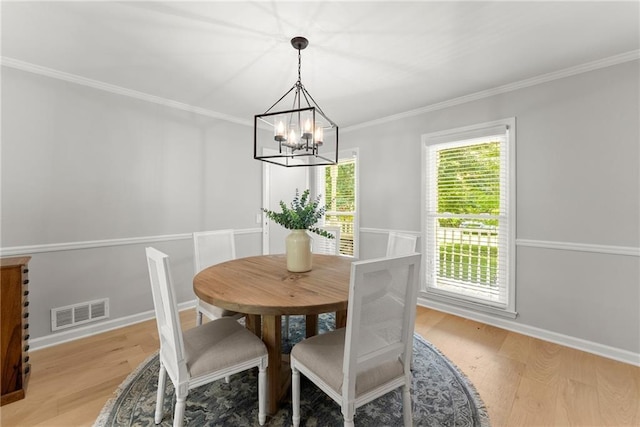 dining area featuring a chandelier, light wood-type flooring, crown molding, and baseboards