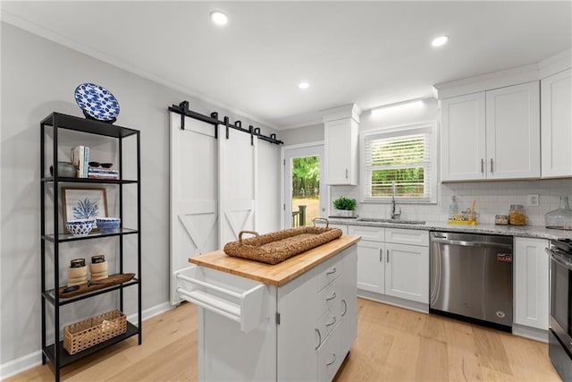 kitchen featuring dishwasher, butcher block countertops, a barn door, decorative backsplash, and light wood-type flooring