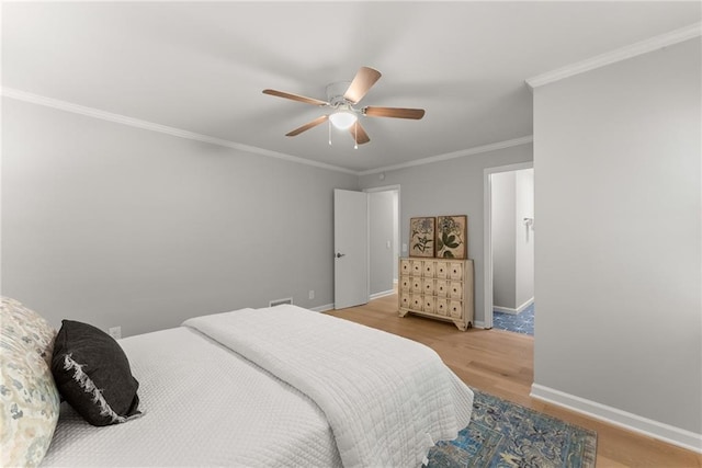 bedroom with wood finished floors, baseboards, crown molding, and a ceiling fan