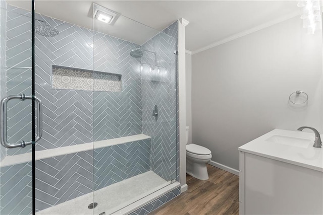 bathroom featuring crown molding, toilet, wood finished floors, vanity, and a stall shower