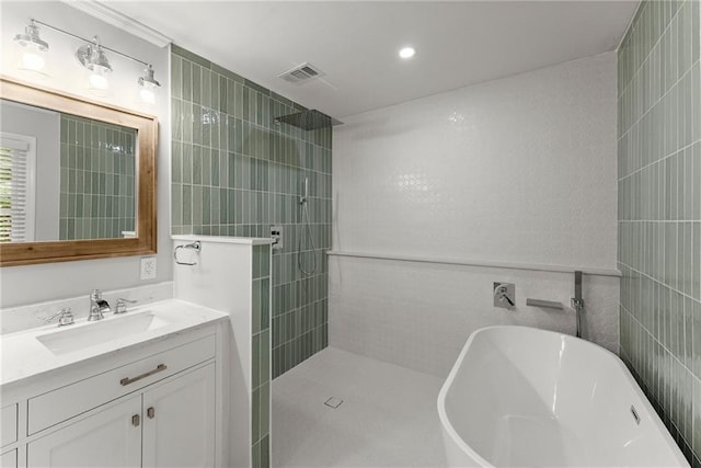 full bathroom featuring tile walls, walk in shower, vanity, and a freestanding tub