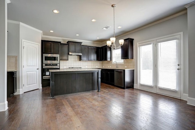 kitchen with appliances with stainless steel finishes, dark wood-type flooring, sink, pendant lighting, and a center island