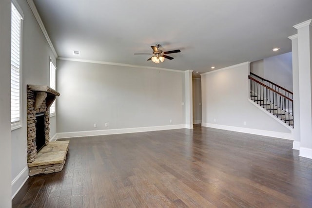 unfurnished living room featuring dark hardwood / wood-style floors, a stone fireplace, ceiling fan, and ornamental molding