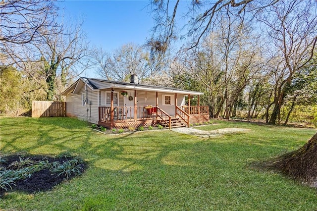 back of house with covered porch, a yard, a chimney, and fence