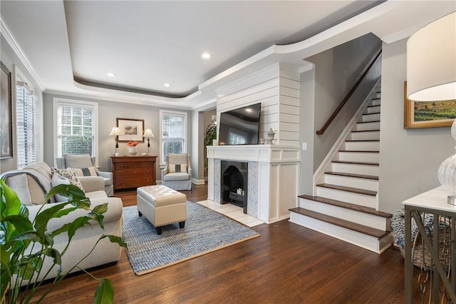 living room with light wood-type flooring, crown molding, a fireplace, and a tray ceiling