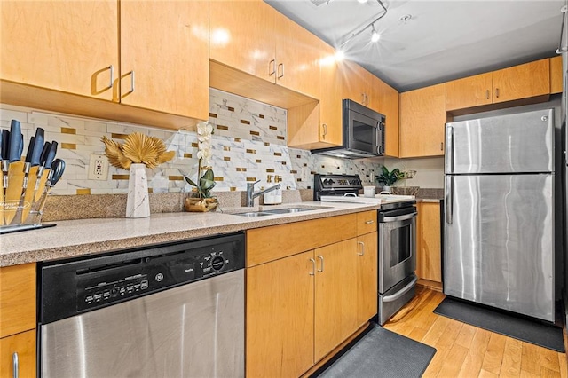 kitchen featuring sink, light hardwood / wood-style flooring, rail lighting, stainless steel appliances, and tasteful backsplash