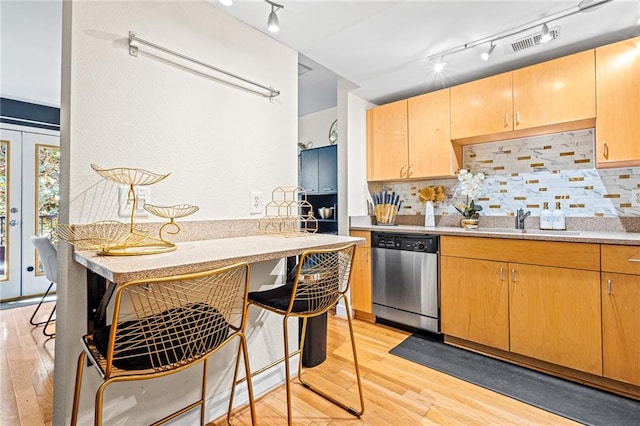 kitchen featuring sink, backsplash, stainless steel dishwasher, and light hardwood / wood-style floors