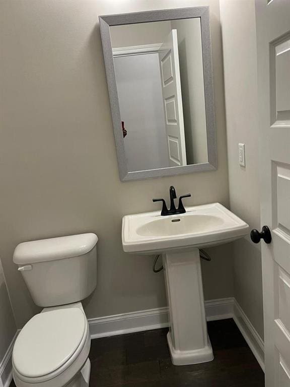 bathroom featuring toilet, sink, and wood-type flooring