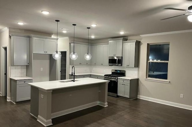 kitchen featuring appliances with stainless steel finishes, sink, hanging light fixtures, dark wood-type flooring, and a center island with sink