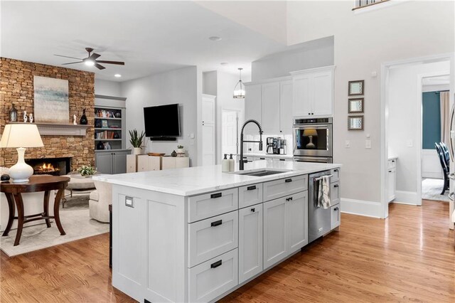 kitchen with ceiling fan, a sink, light wood-style flooring, stainless steel appliances, and open floor plan