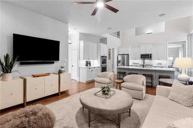 living room featuring ceiling fan, wood finished floors, and a high ceiling