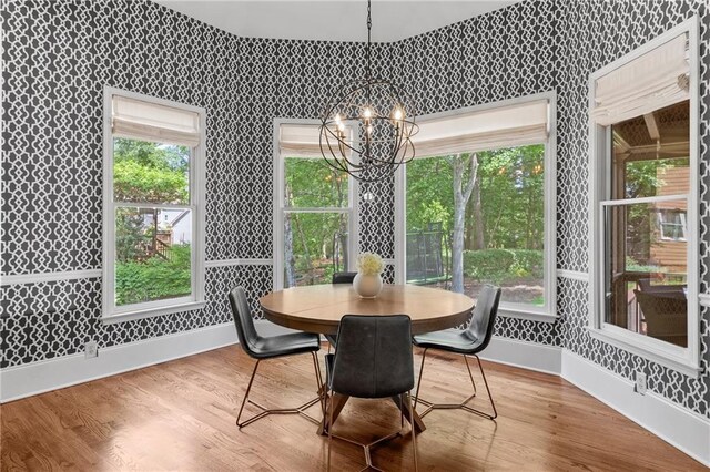 dining area featuring baseboards, wallpapered walls, wood finished floors, and a notable chandelier