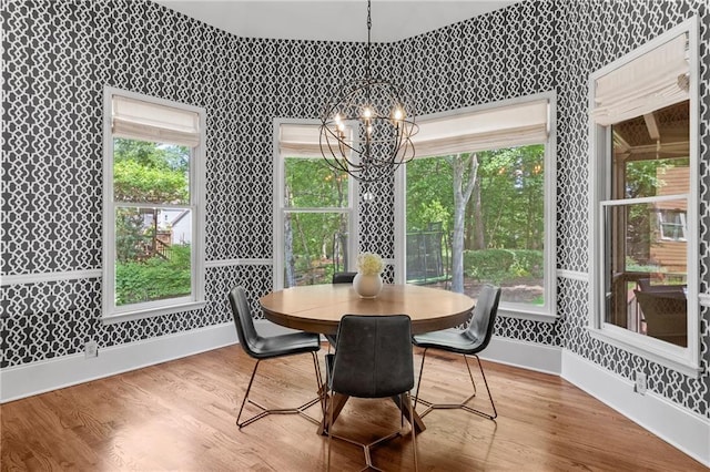 dining area featuring baseboards, wallpapered walls, wood finished floors, and a notable chandelier