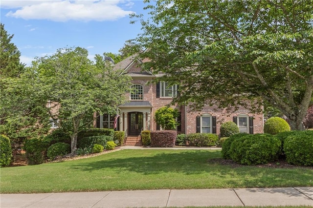 georgian-style home with brick siding and a front lawn