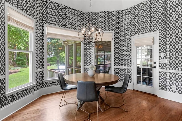 dining space with baseboards, wallpapered walls, wood finished floors, and a chandelier