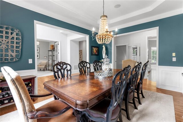 dining room featuring an inviting chandelier, wainscoting, crown molding, and wood finished floors