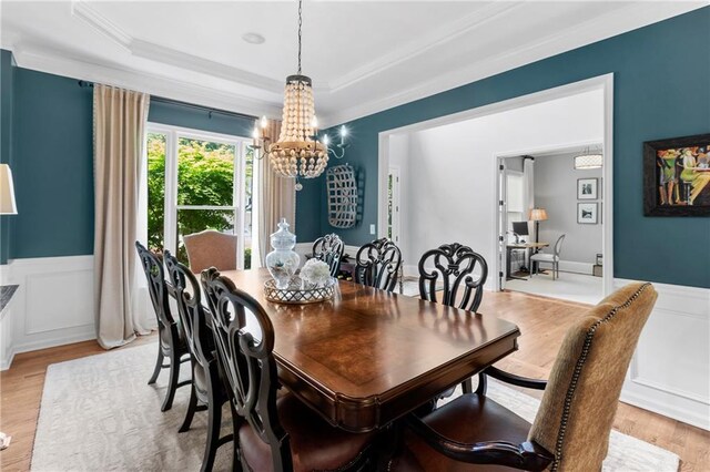 dining space featuring ornamental molding, wainscoting, a tray ceiling, and a notable chandelier