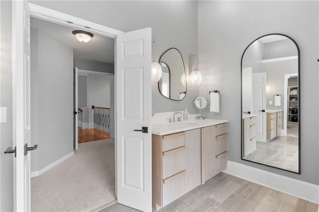 bathroom with vanity, baseboards, wood finished floors, and a spacious closet