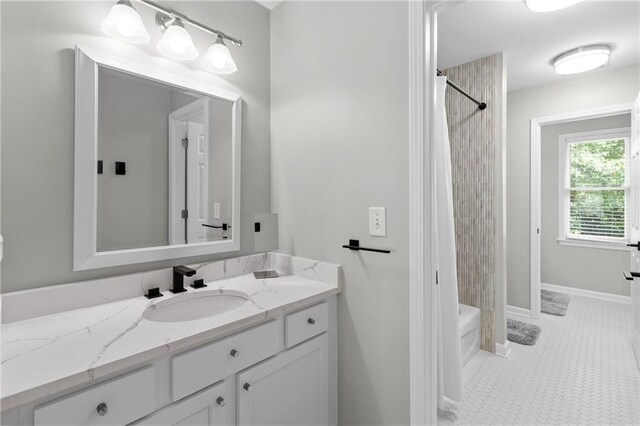 bathroom featuring baseboards, shower / tub combo with curtain, and vanity