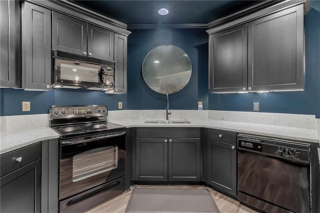 kitchen with light stone counters, a sink, black appliances, and light wood-type flooring
