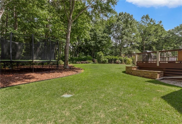 view of yard with a trampoline and a deck