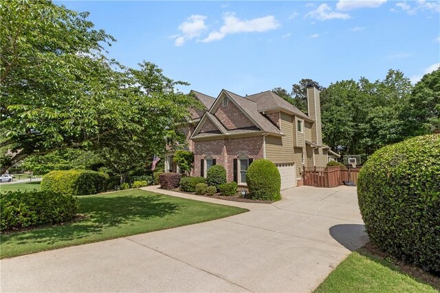 french provincial home with fence, an attached garage, brick siding, a chimney, and concrete driveway