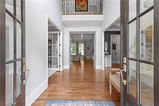 entryway featuring baseboards, french doors, wood finished floors, and a towering ceiling