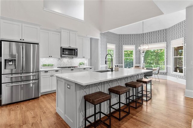 kitchen featuring light wood-type flooring, a sink, appliances with stainless steel finishes, and white cabinets