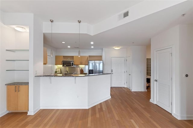 390 17th St NW Unit 6036, Atlanta, GA 30363 - kitchen with appliances with stainless steel finishes, light wood-type flooring, a peninsula, dark stone countertops, and a breakfast bar