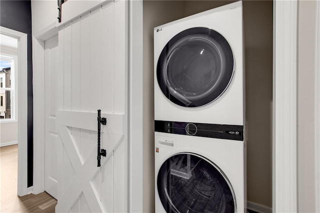 laundry area with stacked washer / dryer and hardwood / wood-style floors